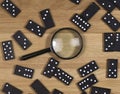 Domino game pieces scattered on wood desk with magnifying glass, top view Royalty Free Stock Photo