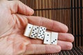 Domino pieces in man`s hand, on wooden bamboo brown table background. Royalty Free Stock Photo