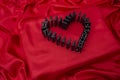 Domino tiles forming a heart shape on red satin fabric Royalty Free Stock Photo