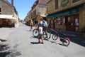 Tourists including a mother and daughter with their bikes in the center of Domme in the Dordogne