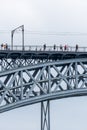 Don Luis I steel bridge in Porto with rain clouds in the background with people walking and taking photos of the Douro River on Royalty Free Stock Photo