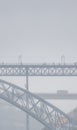 Don Luis I steel bridge in Porto surrounded by fog and rain clouds, with people walking on top of the tram, and a bus and a Royalty Free Stock Photo