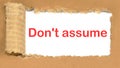 Don`t Assume the inscription appearing behind the torn cardboard paper Royalty Free Stock Photo