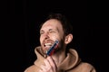 Close-up portrait of young emotive man rips three colors duct tape off his mouth isolated on dark background. Censorship Royalty Free Stock Photo