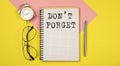 Don`t Forget Notice on notepad with pen, glasses and alarm clock