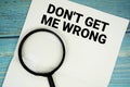 Don\'t Get Me Wrong text written on notepad with magnifying glass flat lay on wooden background Royalty Free Stock Photo