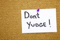 A yellow sticky note writing, caption, inscription Don`t Judge placard on cork pinboard with copy text background