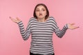 Don`t know, whatever! Portrait of confused woman in striped sweatshirt shrugging shoulders in doubts
