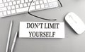 DON\'T LIMIT YOURSELF text on paper with keyboard on grey background