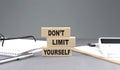 DON`T LIMIT YOURSELF text on wooden block with notebook,chart and calculator, grey background Royalty Free Stock Photo