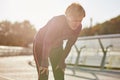 Don`t overdo it. Active mature woman in sportswear looking tired and exhausted, taking a rest after running outdoors on