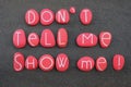 Don`t tell me, show me. Motivational phrase composed with red colored and carved stone letters over black volcanic sand