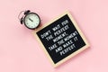 Don`t wait for the perfect moment, take the moment and make it perfect. Motivational quote on letter board, black alarm clock on