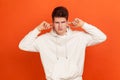 Don`t want to hear! Angry teenager in stylish sweatshirt with hood closing ears with fingers, disobedience, ignoring annoying Royalty Free Stock Photo