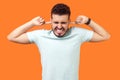 Don`t want to listen anymore. Portrait of brunette man tightly covering his ears. isolated on orange background