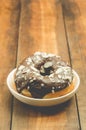 Donat in chocolate glaze is strewed with almonds. Wooden background