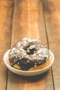 Donat in chocolate glaze in a white bowl on a wooden background