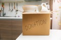 Donate household items - box with tableware for donation on kitchen table