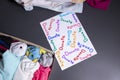 `Donate` sign handwritten with multicoloured letters. A box with clothes and a pile of clothes nearby on a grey table