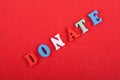 DONATE word on red background composed from colorful abc alphabet block wooden letters, copy space for ad text. Learning