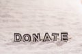 Donate word on white sand