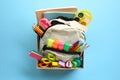 Donation box with backpack with school supplies on bright blue background Royalty Free Stock Photo