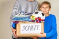 Donation concept. Donate box with clothes, books and toys in child and mother hand Royalty Free Stock Photo