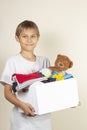 Donation concept. Kid holding donate box with books, clothes and toys