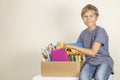 Donation concept. Kid holding donate box with books, pencils and school supplies