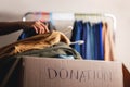 Donation Concept. Preparing Used Old Clothes from Wardrobe Rack into a Donate Box