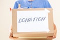 Donation concept. Volunteer hands holding donate box with clothes, books and toys for charity
