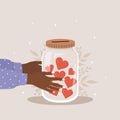 Donation glass jar. African female hands holding bottle with red hearts. Give and share your love. Support and hope for