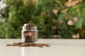 Donation jar with coins on table against blurred background. Royalty Free Stock Photo