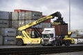 A heavy lifting crane unloading a shipping container from a road lorry