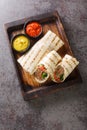 Doner kebab made of meat cooked on a vertical rotisserie with additions of vegetables and sauce wrapped in lavash closeup on the Royalty Free Stock Photo