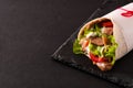 Doner kebab or shawarma sandwich on black slate background.