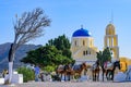 Donkeys carrying cargo in front of the yellow church in Oia, Santorini, Greece Royalty Free Stock Photo