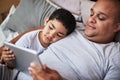 Dont fall asleep. a cheerful young man and his son watching videos on a digital tablet together while hanging out on a