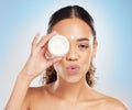 Dont forget to moisturise. a young woman applying cream to her face against a blue background.