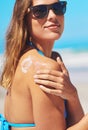 Dont forget to protect your skin. a young woman applying suntan lotion at the beach. Royalty Free Stock Photo