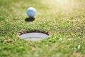 Dont go in its a trap. Closeup shot of a golf ball on the edge of a hole outside on a golf course during the day. Royalty Free Stock Photo