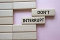 Dont interrupt symbol. Concept word Dont interrupt on wooden blocks. Beautiful pink background. Business and Dont interrupt