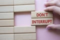 Dont interrupt symbol. Concept word Dont interrupt on wooden blocks. Businessman hand. Beautiful pink background. Business and