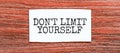 Dont limit yourself text on the piece of paper on the red wood background