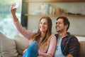 We dont need a reason for a selfie. a happy young couple taking a selfie with a smartphone while sitting on their couch Royalty Free Stock Photo