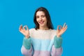 Dont worry everything alright. Relaxed and chill good-looking assertive young woman in winter sweater, wink and smiling