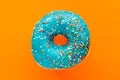 Donut blue with sprinkles isolated on orange background, close-up