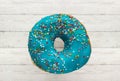 Donut blue with sprinkles isolated on wooden background, close-up