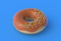 Donut with caramel and sprinkles on blue background. Homemade bakery. Break time