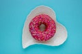 Donut with colorful sprinkles isolated lying on a white plate on blue background. Top view Royalty Free Stock Photo